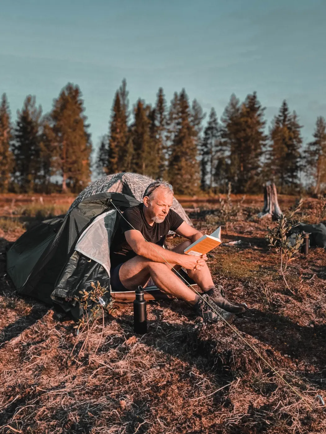 Teilnehmer liest vor seinem Zelt in der Abendsonne